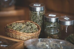 Basket and Jugs Filled with Cannabis in Herbal Store - Stock Photo