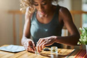african american woman at home rolling marijuana joint from dispensary bought weed