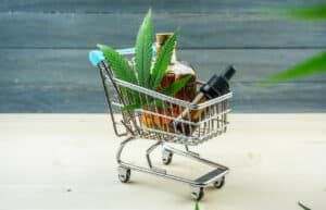 Supermarket trolley with marijuana leafs and medical cannabis oil cbd