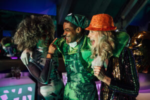A group of young friends wearing fancy dress costumes on a night out during halloween, dancing in a nightclub in Newcastle, North East England. They are all laughing with each other while they dance and the man has his arms around his friends.